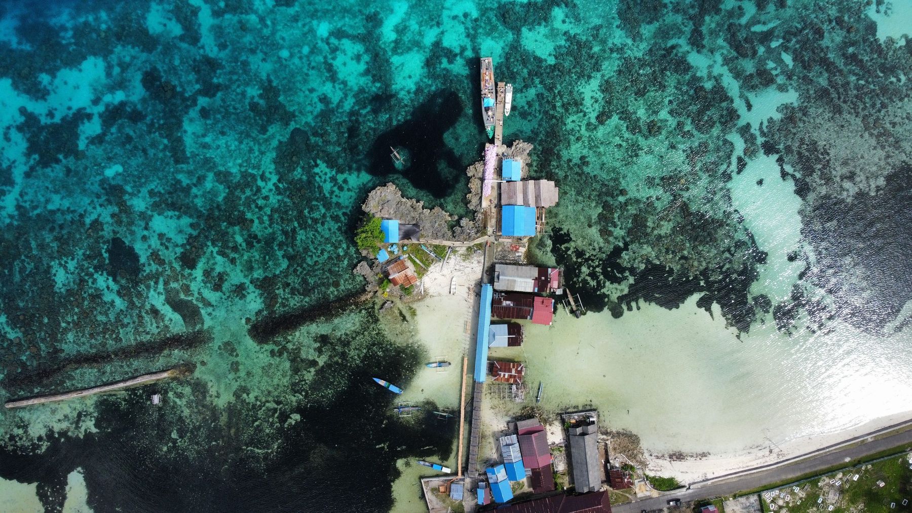 A coastal village with a pier reaching over the reef: many island communities live right at the water's edge.
